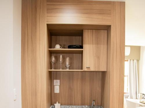 a wooden cabinet with glasses on it in a kitchen at Apart-hotel Cantinho da Serra in Nova Friburgo