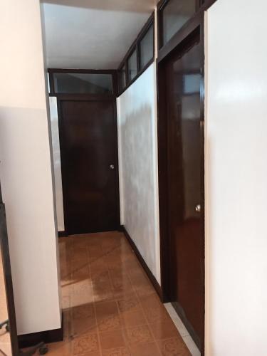 a hallway with black doors and a tile floor at Barnwood Homestay&cafe in Banaue
