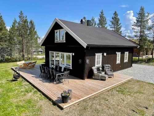 a black house with a deck and chairs on it at New big cabin near the city centre! in Røros