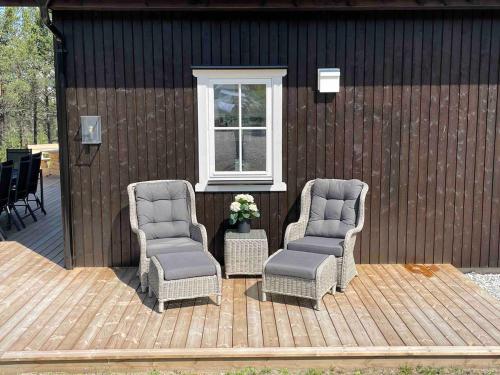 two chairs sitting on a wooden deck next to a window at New big cabin near the city centre! in Røros