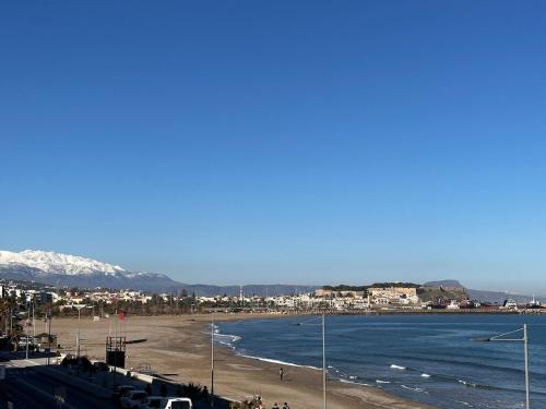 a view of a beach with the ocean and mountains at Akasha Waves in Rethymno Town
