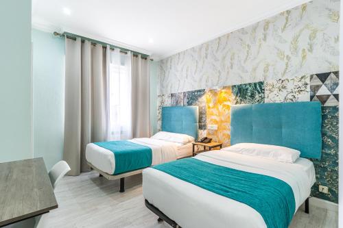 two beds in a room with blue and white at Hotel Mexico in Madrid