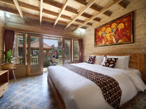 a bedroom with a large bed and a painting on the wall at Wisnu Lumbung Uluwatu in Uluwatu