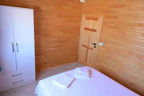 a bedroom with a white bed with a wooden wall at Cirali Zambak Villa in Cıralı