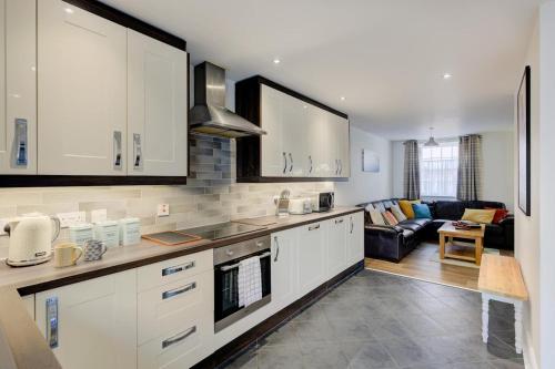 a kitchen with white cabinets and a living room at Juniper House in Harwich