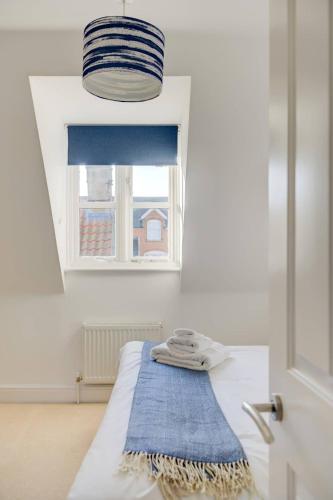 a room with a bed with a blue towel on it at Juniper House in Harwich