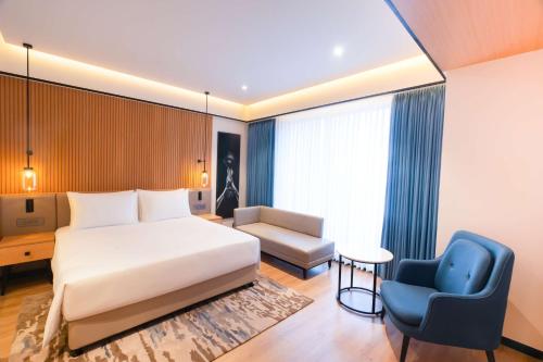 a hotel room with a bed and a blue chair at Radisson Hotel Prayagraj in Allahābād