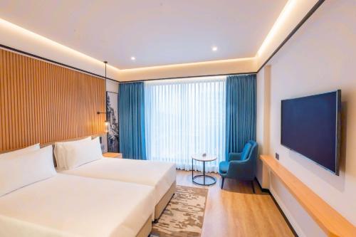 a hotel room with a bed and a flat screen tv at Radisson Hotel Prayagraj in Allahābād