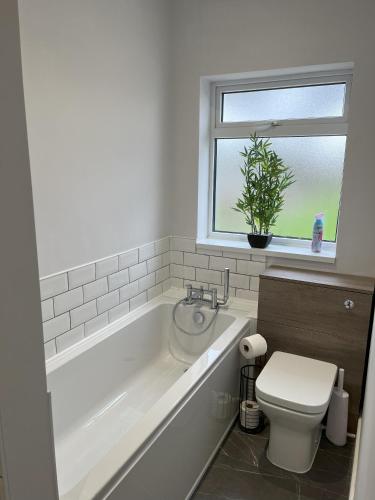 a bathroom with a tub and a toilet and a window at Oak View in Saint Osyth