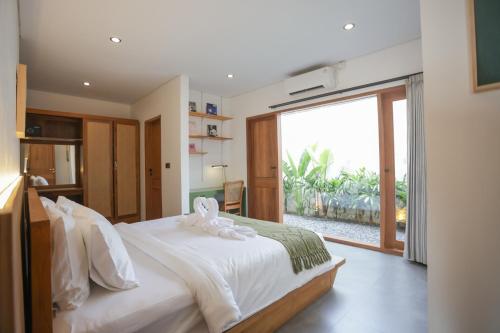 a bedroom with a white bed with a large window at Lorn Villa in Nusa Penida