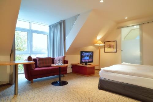 ein Hotelzimmer mit einem Bett, einem Stuhl und einem TV in der Unterkunft Hotel Restaurant Reuter in Rheda-Wiedenbrück