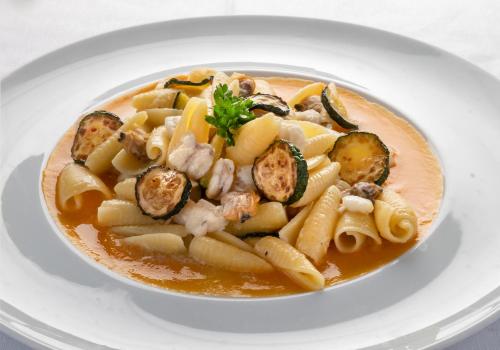 a bowl of pasta with shrimp and vegetables on a plate at Relais Manfredi in Castellammare di Stabia