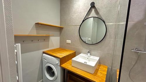 une salle de bain avec un lavabo et une machine à laver dans l'établissement Résidence cosy Les Ambassadeurs - Centre Ville Aix les Bains, à Aix-les-Bains