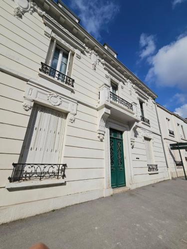 - un bâtiment blanc avec une porte verte et un balcon dans l'établissement Villa - centre d'Epernay - 6 Chambres - Terrasse, à Épernay