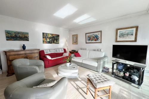 Il comprend un salon doté d'un mobilier blanc et d'une télévision à écran plat. dans l'établissement T3 with magnificent sea view, à Antibes