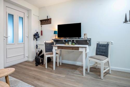 a room with a desk with a television and chairs at Ferienwohnung - Wolkow in Wolkow