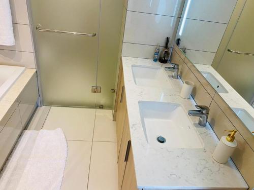 a bathroom with two sinks and a shower at Cosy Uptown 2 Bedroom Sandton in Johannesburg