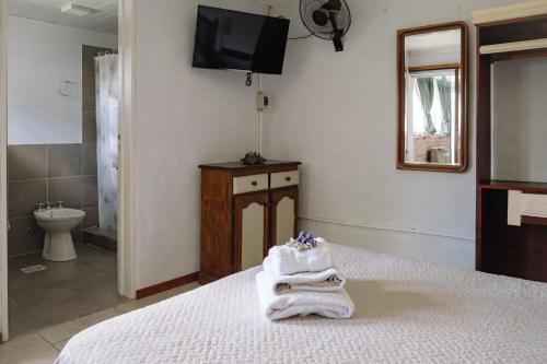 a bedroom with a bed with towels and a bathroom at El Descanso in San Antonio de Areco