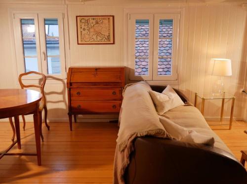 a living room with a couch and a table and windows at Gemütliches Holzhäuschen inmitten der Zuger Altstadt in Zug