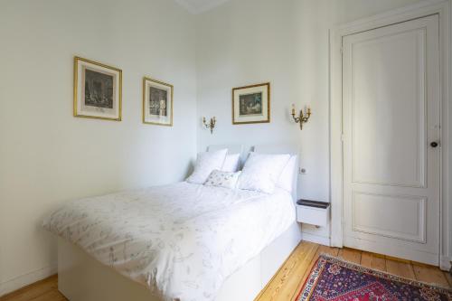 une chambre avec un lit blanc avec deux tableaux au mur dans l'établissement Élégance et Luxe au Cœur de Bordeaux-Quinconces, à Bordeaux