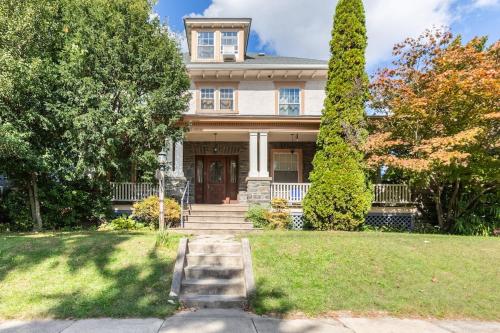 a large white house with a porch and trees at Quaint 3rd Floor Loft in Highland Park