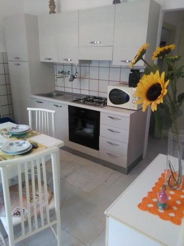 una cocina con armarios blancos y una mesa con girasol en Casa Fontana, en Arcola