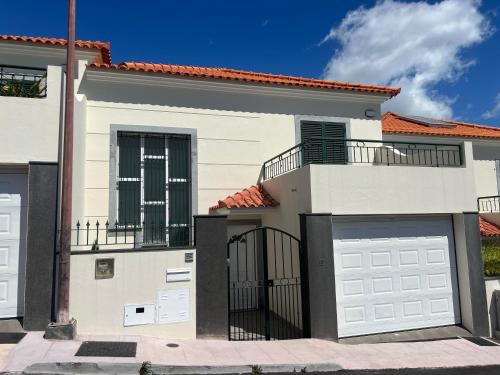 a white house with two garage doors at Maribel's Place in Funchal