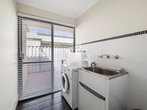 a kitchen with a washing machine and a sink at Busselton Broadwater Holiday Home in Busselton