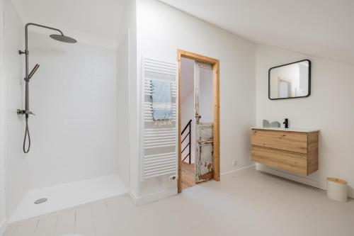 La salle de bains blanche est pourvue d'une douche et d'une porte en bois. dans l'établissement Belle villa rénovée aux portes de l'île d'Oléron, à Bourcefranc