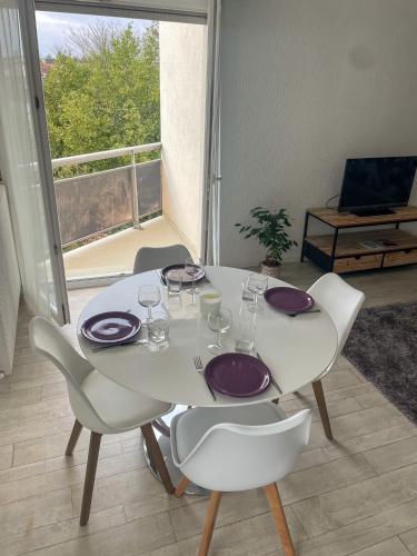 - une table blanche avec des assiettes et des chaises violettes dans la chambre dans l'établissement T2 paisible et lumineux proche tram B, à Talence