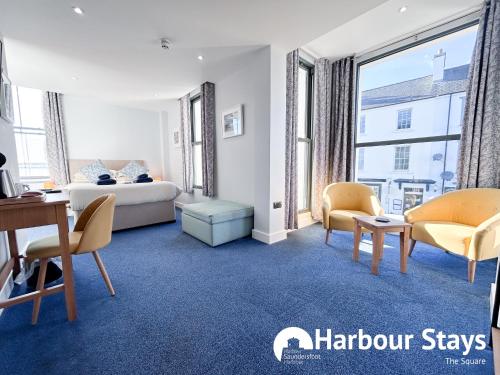a bedroom with a bed and a desk and chairs at Harbour Stays at Ocean Square in Saundersfoot