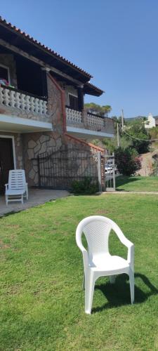 a white chair sitting in the grass in front of a house at EdenRock in Riva dei Pini
