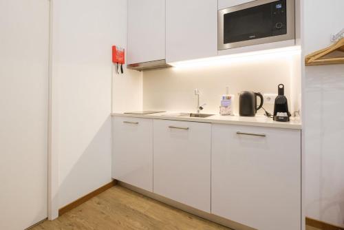 a white kitchen with a sink and a microwave at GuestReady - Port Studio 3 in Vila Nova de Gaia