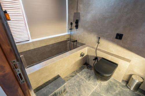 a bathroom with a toilet with a sink and a tub at The Foresta Resort ,Mulshi in Paud