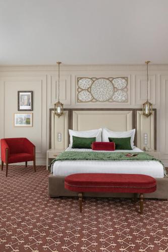 a bedroom with a large bed and a red chair at Jumbaktas Astana Hotel in Astana