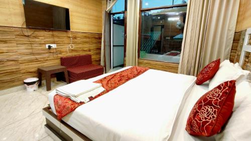 a bedroom with a bed with red pillows and a television at Srishti Nikunj Home Stay in Shogi