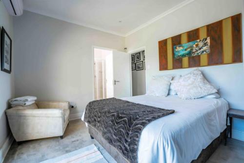 a bedroom with a large bed and a chair at Highrocks Beach House in Umkomaas