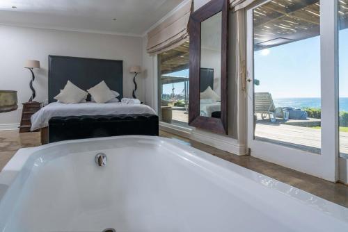 a white bath tub in a bedroom with a bed at Highrocks Beach House in Umkomaas