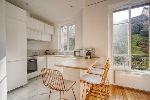 une cuisine avec des armoires blanches et une table et des chaises dans l'établissement Elegance Versaillaise, à Versailles