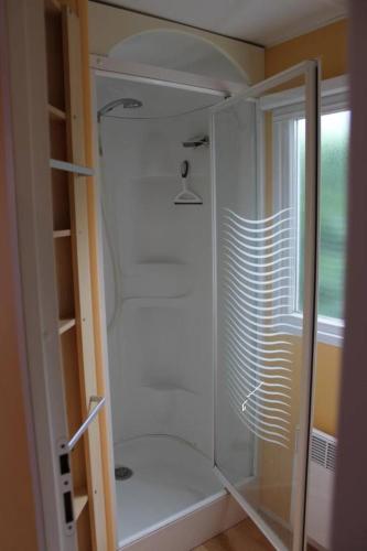 une douche avec une porte vitrée dans une salle de bain dans l'établissement Camping Sable d'Or 3 chambres, au Cap d'Agde