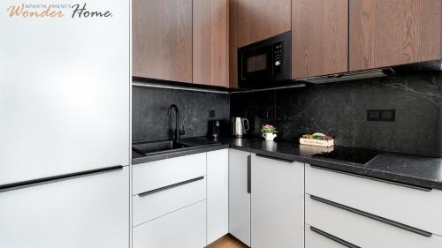 a kitchen with white cabinets and a black counter top at Wonder Home - Domki Hillside tuż przy stoku narciarskim - na terenie kompleksu plac zabaw i zewnętrzna siłownia, sklep, parking in Karpacz