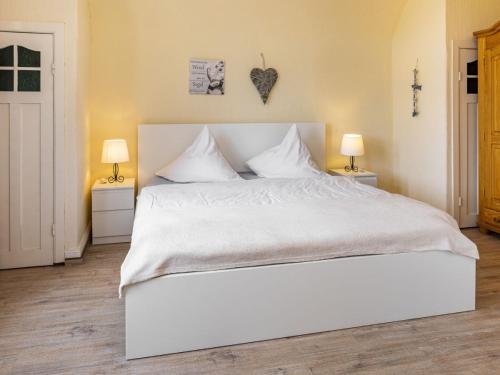 a bedroom with a large white bed with two lamps at Ferienwohnungen Fehlingstr 28 in Travemünde