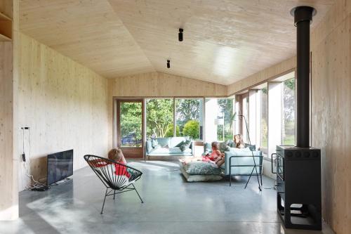 a living room with two children sitting in chairs and a fireplace at Haaghoek, design vakantiewoning in Horebeke