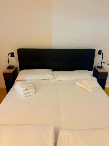 a large white bed with two towels on it at Nomad Hostel in Treviso