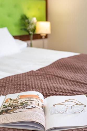 an open book with glasses on a bed at Hotel Kazimierzówka in Kazimierz Dolny