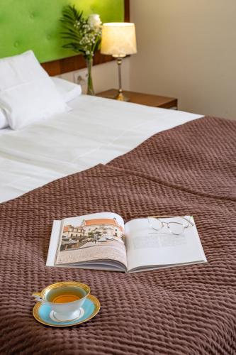 a book and a cup of tea on a bed at Hotel Kazimierzówka in Kazimierz Dolny