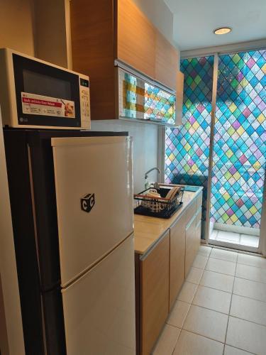 a kitchen with a refrigerator with a microwave on top at The Central Bangkok Station1 in Bangkok