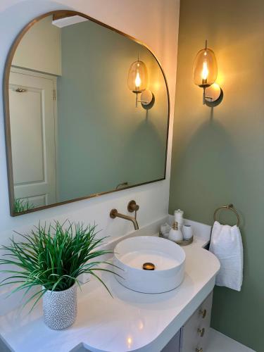 a bathroom with a white sink and a mirror at The Cottage at Paradise Found in Yzerfontein