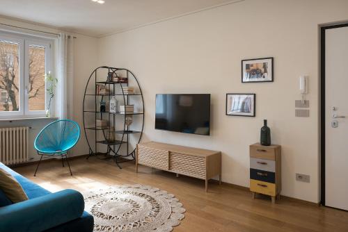 a living room with a tv and a blue chair at Casa Flora in Savigliano