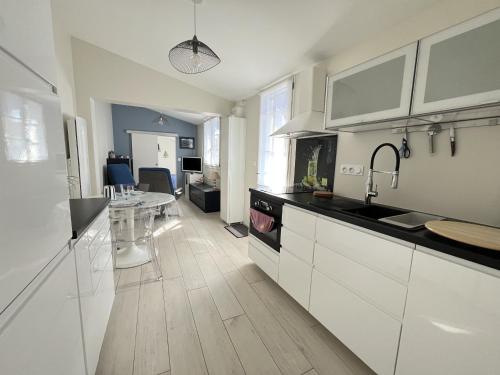 une cuisine avec des placards blancs et une salle à manger dans l'établissement Les Glaieuls, à Saint-Gilles-Croix-de-Vie